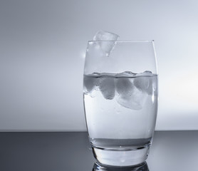 Fallende Eiswürfel in das Glas mit Wasser 