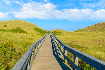 Fototapeta na wymiar Wooden footbridge from sand dune to beautiful beach near Westerland village, Sylt island, Germany