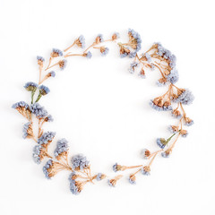 Frame wreath of pale blue dried flowers on white background. Flat lay, top view