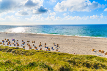 Fototapeta na wymiar View of beach with wicker chairs against sun on blue sky, Sylt island, Germany