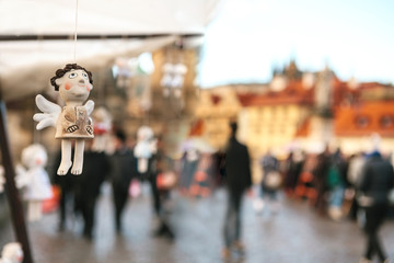 Statues souvenirs in the form of an angel hanging on the background of Prague. Holiday, a blurry crowd of people