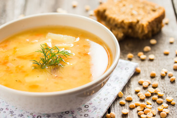 Homemade pea soup with whole grain bread on a wooden table.