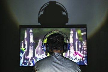 Young gamer playing video game wearing headphone. © sezer66