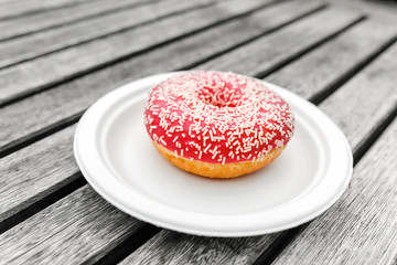One pink appetizing donut on a vintage rural wooden board background