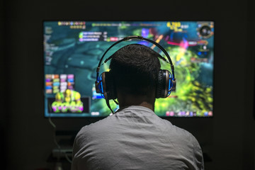 Young gamer playing video game wearing headphone. - obrazy, fototapety, plakaty