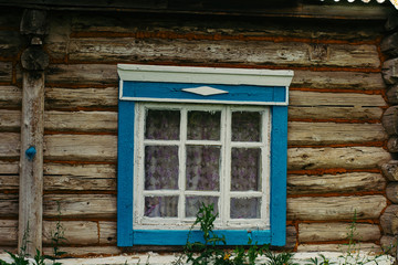 Fototapeta na wymiar The wall of an old village house with a carved blue window. Tulle. Traditional.