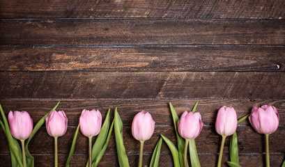 Obraz premium Row of tulips on wooden background with space for message. Mother's Day background. Top view.