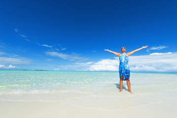 Happy standing woman arms outstretched on the white sand beach.Copy space