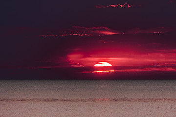 composizione colori panorama  alba mare estate disco sole coperto parzialmente nuvole 