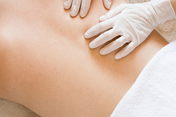 Therapist hands in protective gloves massaging man's back.