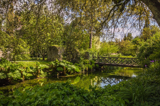 Giardino di Ninfa: piccolo ponte sopra al fiume immerso nella fitta e verde vegetazione