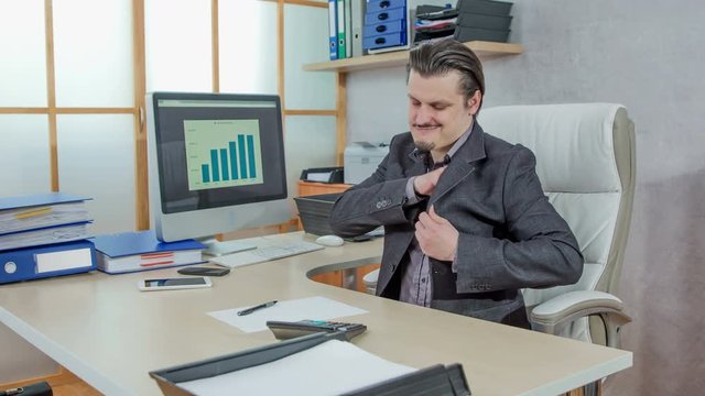 A young man is taking all the money out of his pockets in a jacket and he is putting the money on a desk in front of him. He gives thumbs up.