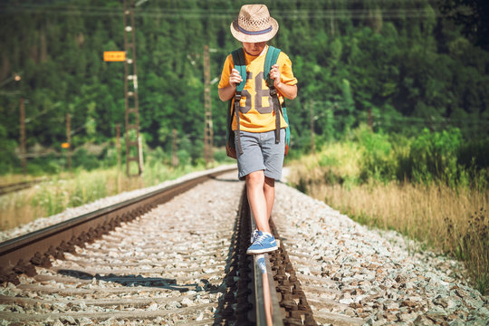 Little boy with backpack walks on railway track