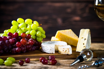  Wine bottles with grapes and cheese on wooden rustic background. copy space