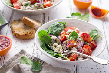 Healthy spring salad with quinoa, fresh spinach and blood oranges on white rustic background