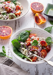 Healthy spring salad with quinoa, fresh spinach and blood oranges on white rustic background
