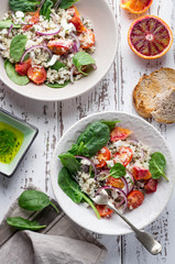 Healthy spring salad with quinoa, fresh spinach and blood oranges on white rustic background