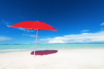 Red sun umbrella on the white sand beach.Copy space