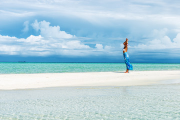 Woman with arms outstretched standing on the white sand beach.Copy space