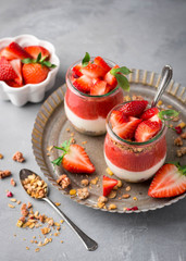 Delicious homemade granola, yogurt and strawberry parfait in glass jars 