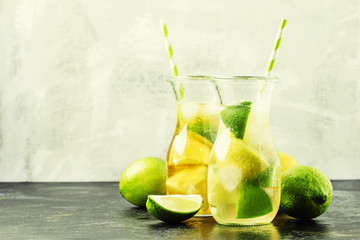 Ice black and green tea with lemon, lime and ice in the jug, selective focus