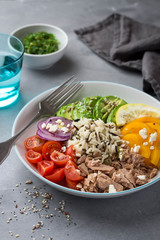 Healthy lunch bowl with wild rice, tuna, avocado, bell pepper and cherry tomatoes. Overhead shot