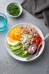 Healthy lunch bowl with wild rice, tuna, avocado, bell pepper and cherry tomatoes. Overhead shot