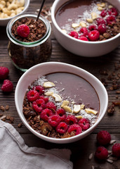 Chocolate breakfast bowls with frozen banana, cocoa, granola, raspberries, cashew nuts and coconut