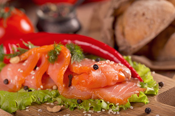 Slices of smoked salmon with dill, chili pepper, tomatoes and bread