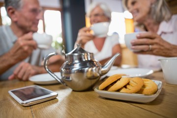 Close-up of teapot, mobile phone and cookies