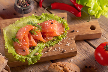 Slices of smoked salmon with dill, chili pepper, tomatoes and bread