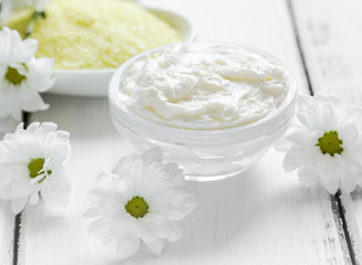 homemade cosmetics with camomile herbs on white wooden background
