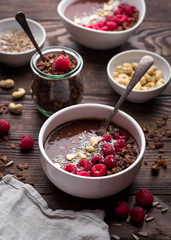 Chocolate breakfast bowls with frozen banana, cocoa, granola, raspberries, cashew nuts and coconut