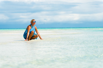 Woman crouched on the white sand beach.Copy space
