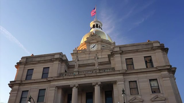 American and Georgia state flags fly on top of golden dome of City Hall in Savannah, Georgia