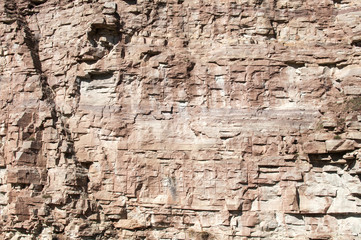 Vertical reddish wall of abandoned stone quarry closeup as natural background