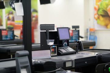 Empty cash desk with computer screen and card payment terminal on blurry background