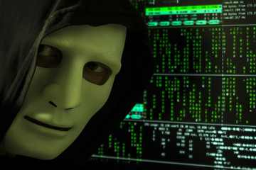 The hacker in the hood and mask on the background of the digital code.
