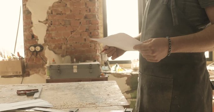 Carpenter looking on a drawing, close-up, in a carpentry workshop