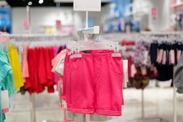Variety of bright girl shorts on hangers in kids clothes store