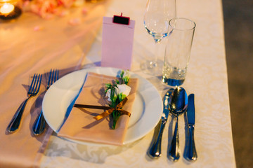 Naklejka na ściany i meble Table setting at a wedding banquet. Decoration flowers. A close-up of a plate with cutlery.