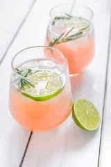 glass of fresh juice with lime and rosemary on wooden table background