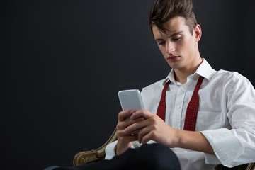Androgynous person sitting on chair and using mobile phone
