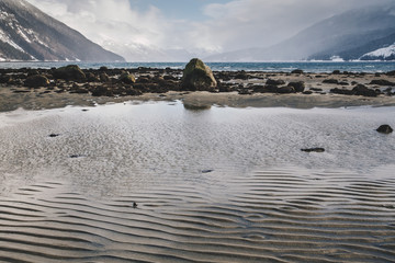 Rippling Sand Patterns on Beach in Alaska with Distant Waves on Rocky Shore
