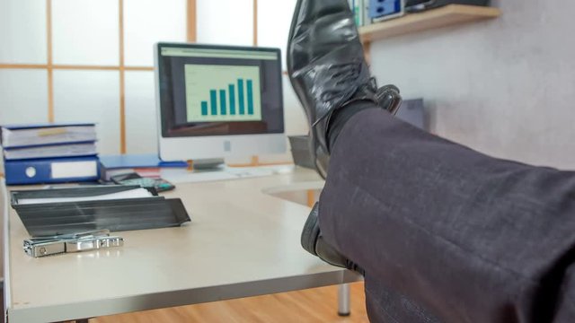 A young boss is putting his feet on a table. He is relaxing a bit after a long day.