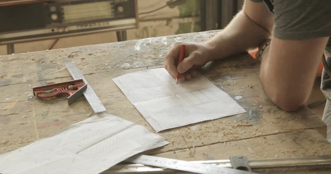 Carpenter working on a drawing, close-up, in a carpentry workshop