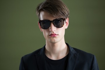 Androgynous man in sunglasses posing against green background - Powered by Adobe