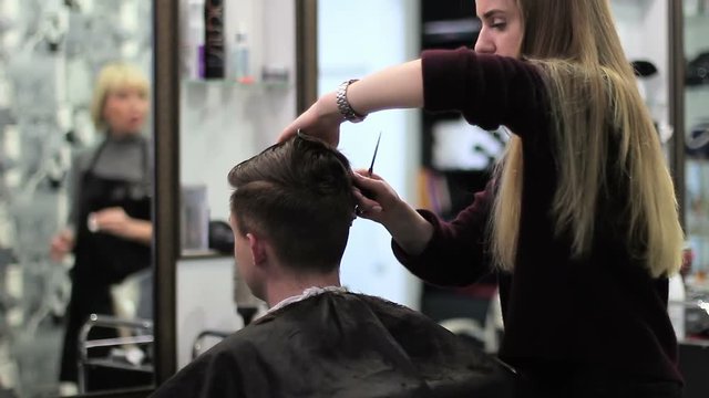 Barber cuts the hair of the young client with trimmer