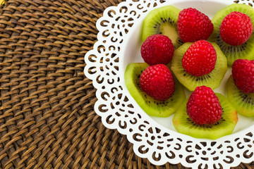Fresh Red Raspberries on a white artistic plate / Red Fresh Raspberries on a white artistic plate with cookies, rosemary, chocolate and cream in the background.