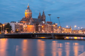 Night city view of Amsterdam canal, bridge and Basilica of Saint Nicholas, Holland, Netherlands. Long exposure